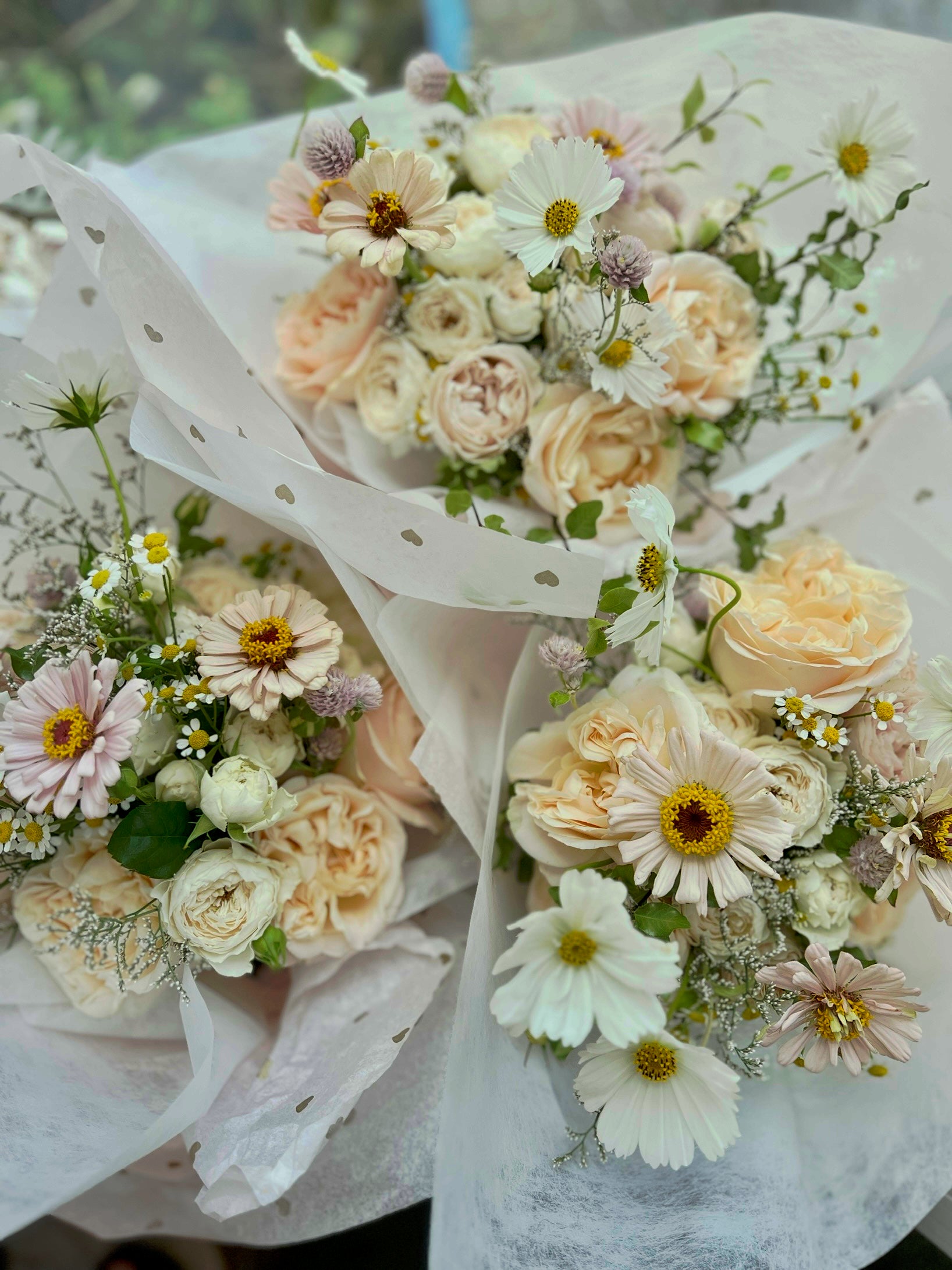 Bouquets of white and cream flowers with greenery on a blurred background